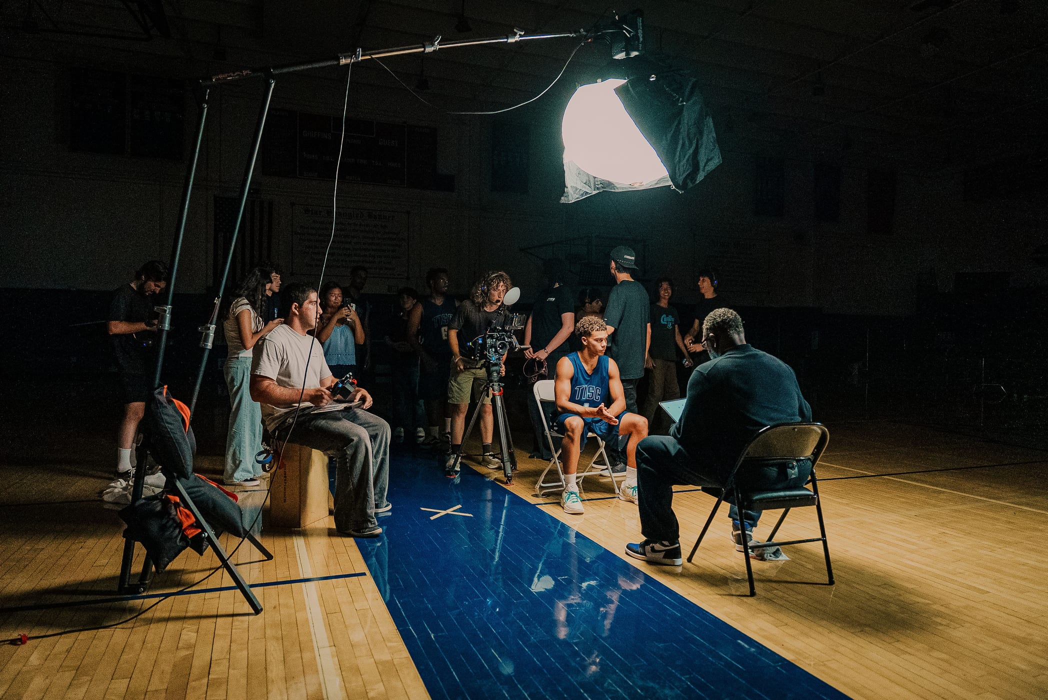 Crew and talent on a basketball court set lit by a large overhead softbox